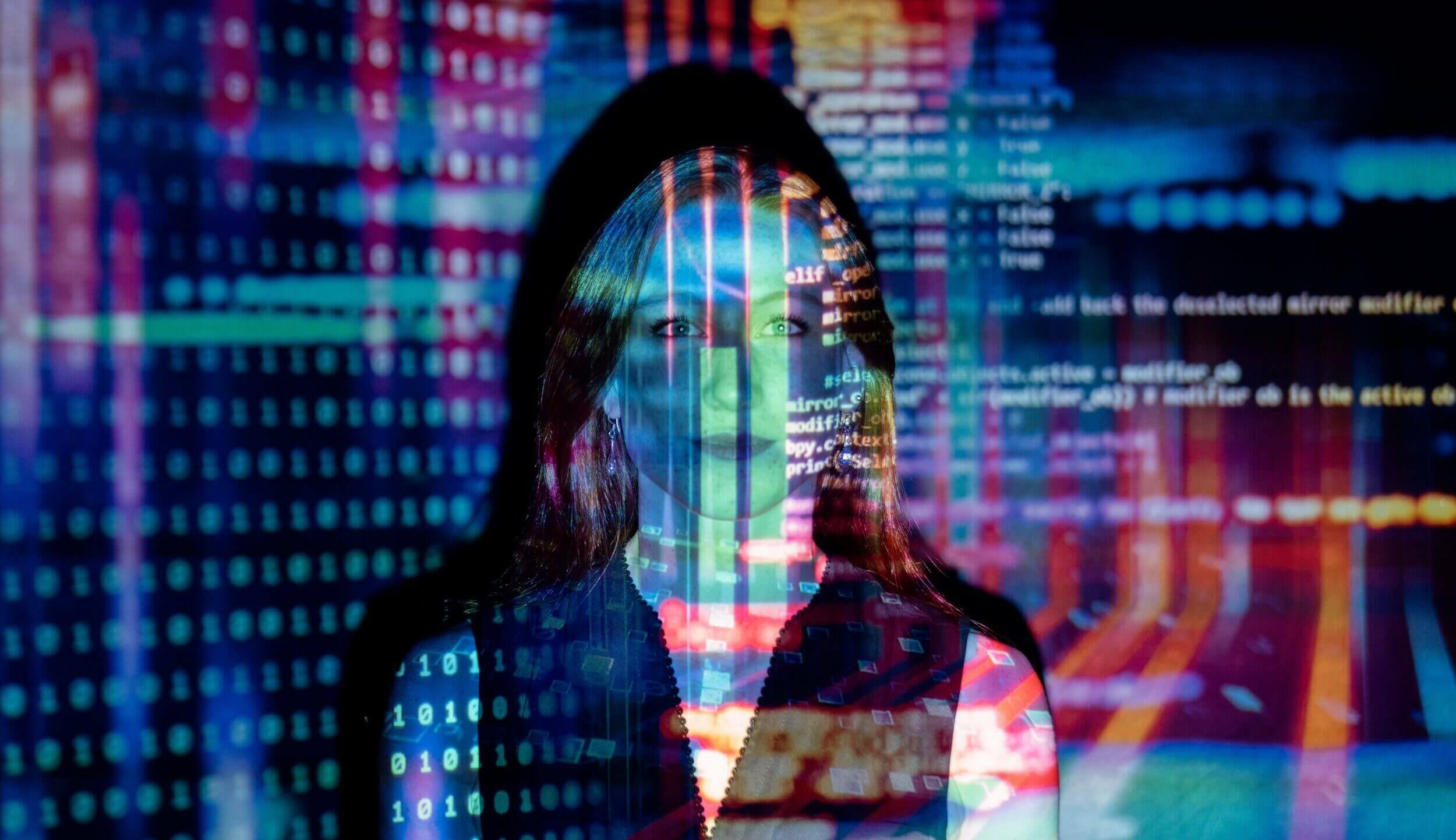 Woman standing with computer screen in her face showcasing code, searches and computer information. 